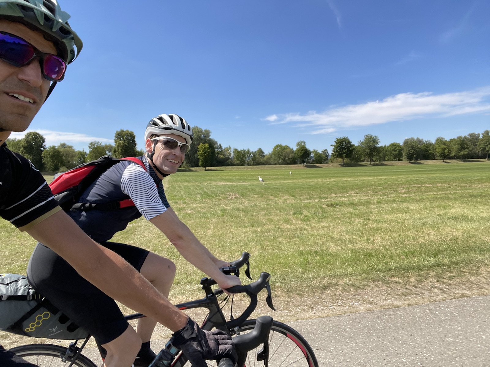 Felix und ich auf dem Velo. Zwei Störche im Hintergrund.